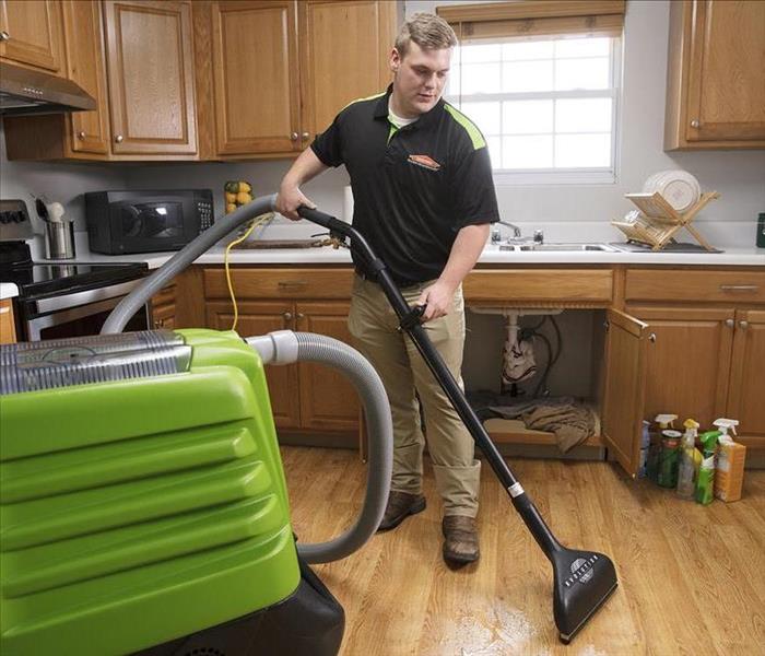 SERVPRO tech extracting water in a kitchen with a wand. 