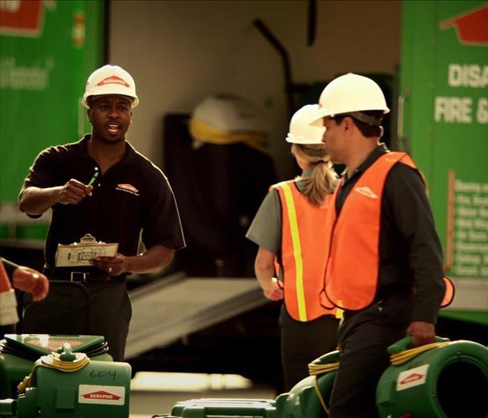 SERVPRO Employees standing by SERVPRO vehicles at a commercial site