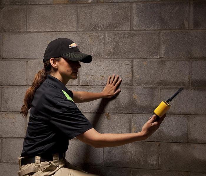Female SERVPRO employee with a moisture meter checking for moistuer